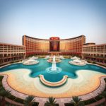 Wynn resort exterior with large curved facade, fountain pool and palm-lined courtyard in a desert setting